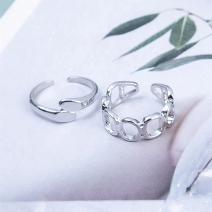 Close-up of minimalist silver open rings set with cross and oval chain link textures
