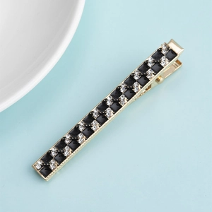 Detailed shot of golden metal hair clip with black and white rhinestone checkerboard pattern