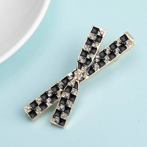 Detail of golden metal hair clip featuring a black and white checkerboard rhinestone bow