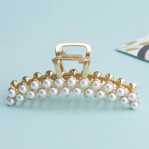 Elegant gold metal hair claw clip with double rows of pearls on light blue background