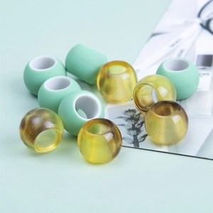 Close-up of matte mint green and amber resin large hole beads for DIY hair styling