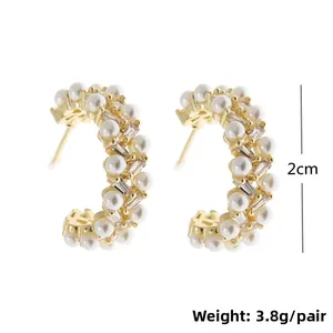 Detail view of 2cm gold C-shaped earrings with faux pearls and rectangular zircons
