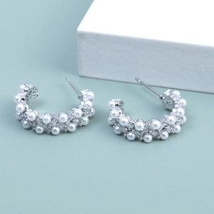 Detail of silver C-shape earrings with zircon crystals and round white pearls in double rows
