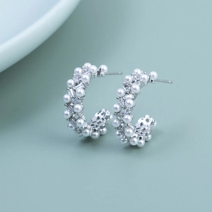 Macro shot of silver S925 C-shaped hoop earrings with pearls and zircon stones