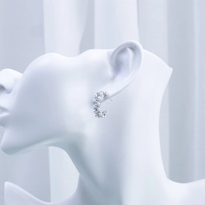 Detail of silver geometric C-shaped earrings with white pearls on a model mannequin