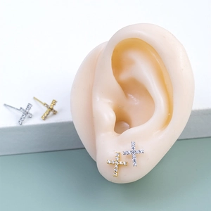 Close-up of minimalist cross stud earrings with sparkling cubic zirconia on an ear model