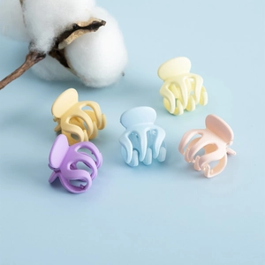 Détail de cinq mini pinces à cheveux mates aux tons pastel violet jaune bleu et rose