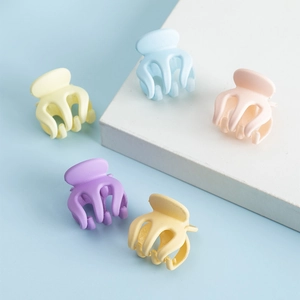 Cinq pinces à cheveux mates aux couleurs pastel sur des présentoirs bleu clair et blanc