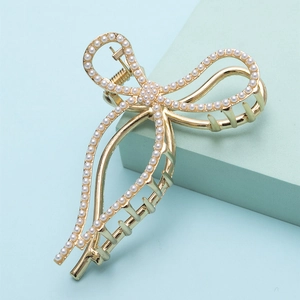 Elegante gouden haarklem met strikvorm en parels op een stijlvolle blauwe display