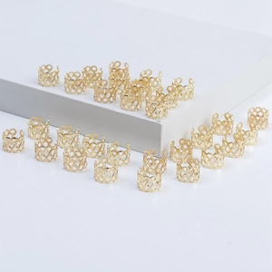 Close-up of golden hollow metal hair rings for braids on white geometric stands