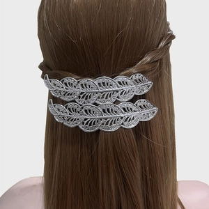 Set di due fermagli per capelli in argento a forma di foglia vuota su capelli castani