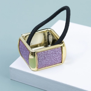 Dettaglio di un elastico per capelli con fibbia quadrata in metallo dorato e glitter viola