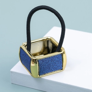 Vista macro dell'elastico per capelli dorato quadrato con brillantini blu e fascia nera