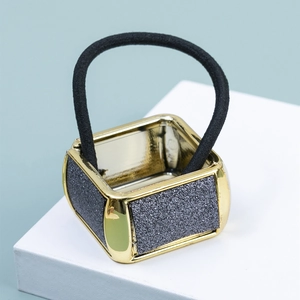 Dettaglio fibbia quadrata dorata con glitter grigio scuro su elastico per capelli nero
