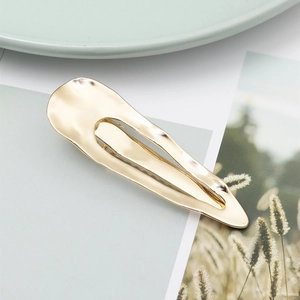 Barrette à cheveux goutte d'eau en métal doré au fini miroir sur papier blanc chic