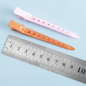 Détail macro de deux barrettes à cheveux de 9,5 cm en métal rose et orange avec règle