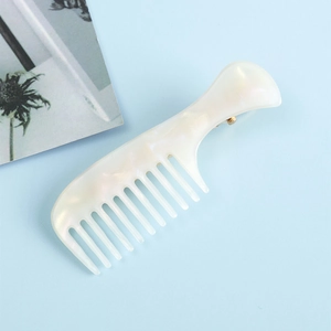 Détail de la pince à cheveux en acétate blanc nacré avec un design en forme de peigne