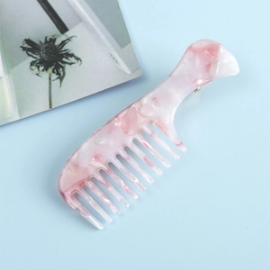 Gros plan d'une pince à cheveux en acétate en forme de peigne avec texture marbrée rose