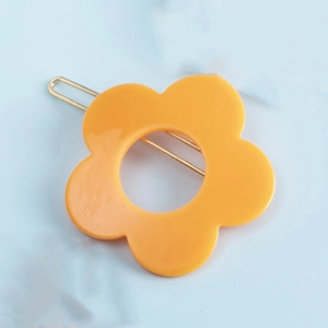 Pince à cheveux fleur jaune minimaliste en résine mate sur une base en métal doré