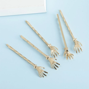 Lot de cinq barrettes à cheveux en métal doré en forme de main de squelette