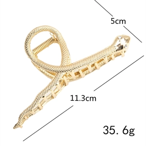Detalle macro de la pinza de pelo de serpiente con escamas plateadas y dimensiones