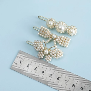 Vue détaillée de trois barrettes à perles dorées avec motifs de papillon et de fleurs
