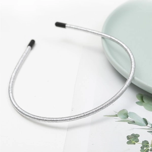 Close-up of silver thin headband with metallic wire texture and black rubber tips