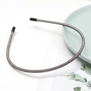 Detail of slim dark grey wire headband with protective rubber tips on ceramic plate