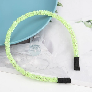 Dettaglio di cerchietto verde neon con paillettes, estremità in tessuto e finitura lucida