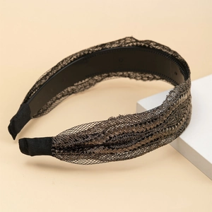 Elegant gold lace leaf headband with rhinestones on a minimalist warm display base