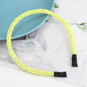 Dettaglio del cerchietto in cristallo giallo neon con strass lucidi su marmo