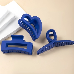 Dettaglio di tre mollette per capelli blu Klein opaco in forme a cuore e geometriche