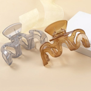 Detail view of two wavy hair claws in translucent smoky gray and amber resin finishes