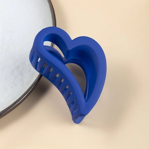 Pinza per capelli a cuore blu Klein opaco con design a intaglio su sfondo beige neutro