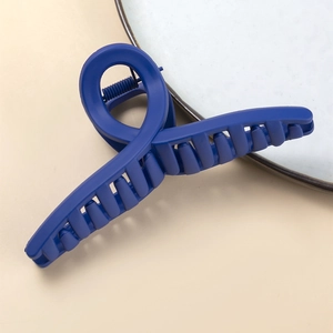 Dettaglio pinza per capelli blu opaco con grande design incrociato e molla metallica