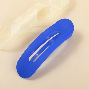 Dettaglio della grande molletta per capelli blu opaco su sfondo beige con nastro