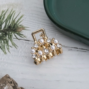 Close-up of golden hair claw clip featuring elegant pearls and sparkling rhinestones