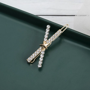 Fermaglio per capelli a croce dorato con strass e dettaglio stella su vassoio decorativo