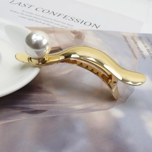 Elegant gold metal banana hair clip with a large white pearl and polished mirror finish