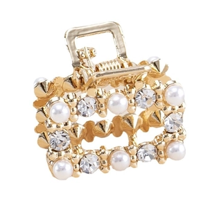 Pince à cheveux élégante en métal doré avec perles et strass sur fond blanc immaculé