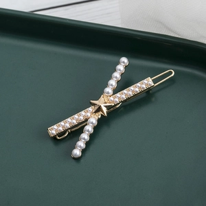 Elegante fermaglio dorato con perle e stella su vassoio verde scuro e pizzo