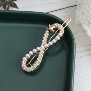 Barrette dorée élégante en forme d'infini avec perles et étoile sur plat céramique