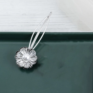 Eleganter silberner Metall-Blumen-Haarclip mit weißer Perle auf grünem Tablett
