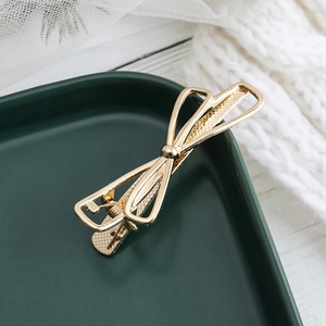 Eleganter goldener Schleifen-Haarclip im minimalistischen Legierungsstil auf Keramik