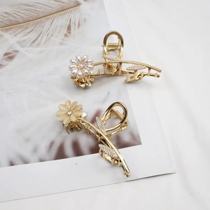 Elegante gouden bloem haarklemmen met opaal en parels op witte veren gepresenteerd