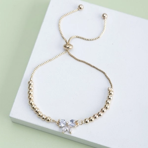 Detail of adjustable gold bracelet featuring a sparkling zircon butterfly charm with beads