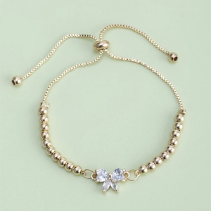 Minimalist gold beaded bracelet featuring a sparkling zircon bow pendant and slider clasp