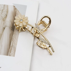 Elegante gouden bloem haarklem met kattenoogsteen en parels op wit textiel