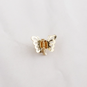 Mini pince à cheveux papillon en métal doré avec ailes évidées sur tissu blanc
