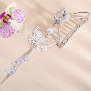Silver butterfly metal hair claw clip with pearl tassel and long chains on beige background